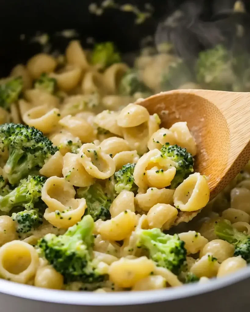 Stirring creamy vegan broccoli pasta in a pot with a wooden spoon